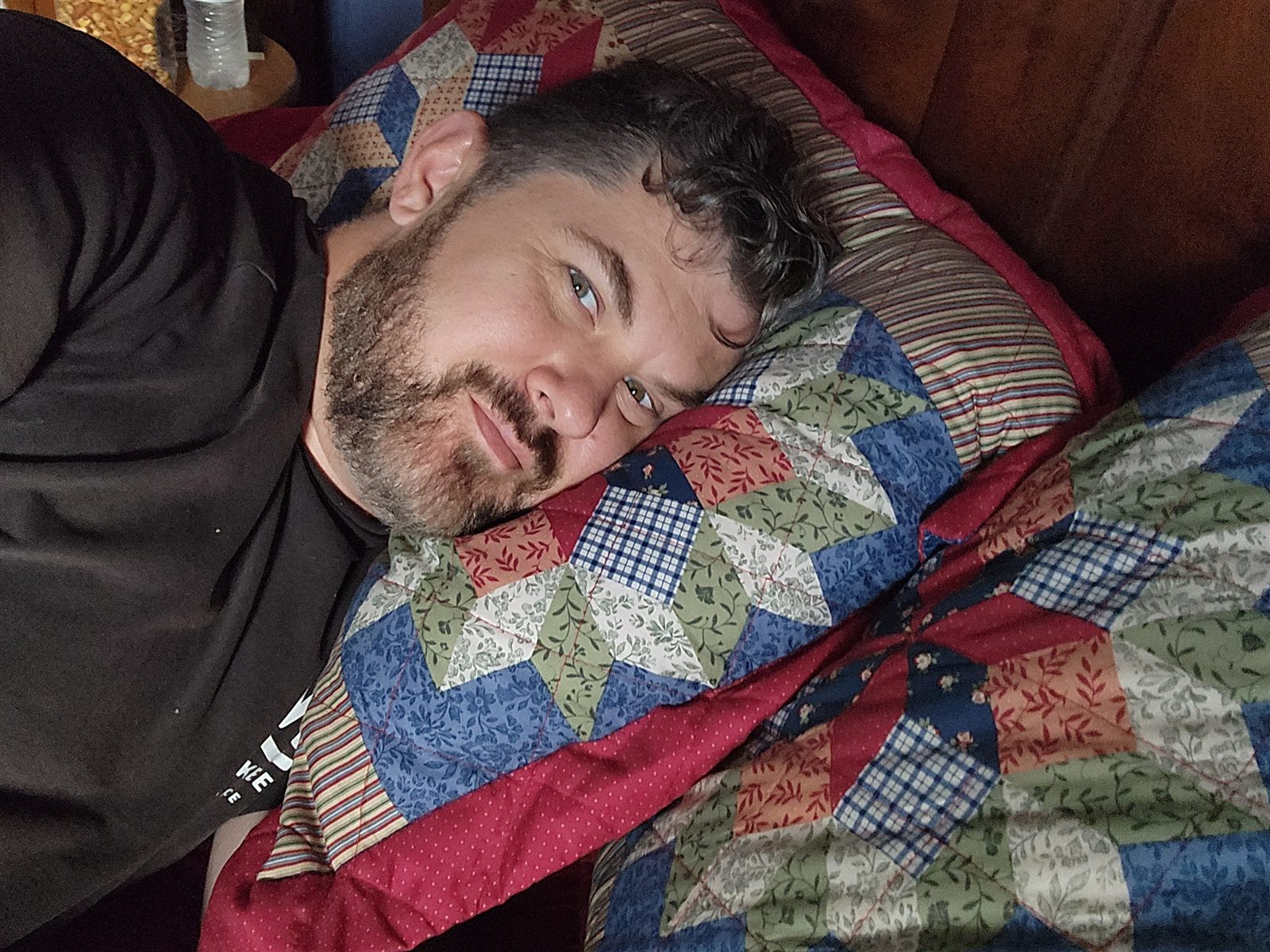 Leon L Smooth relaxing under a handmade quilt